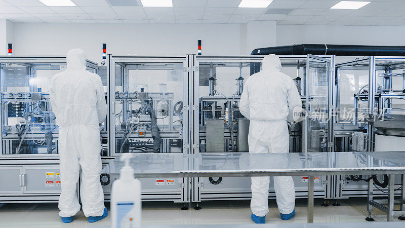 制造实验室的科学家在保护工作服与工业高精度3D打印机械工作。制造制药/技术/工业产品。